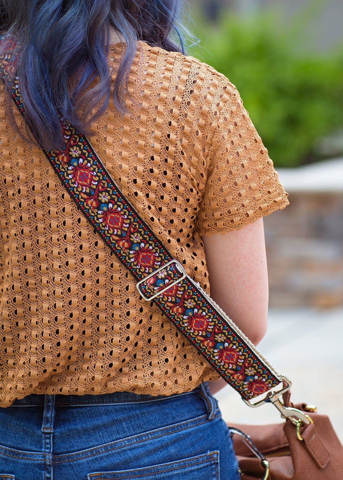 a girl&#39;s backside with a vintage handbag strap and a brown heavy bag